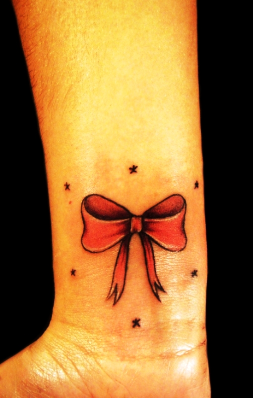 Red Ink Bow Tattoo On Wrist